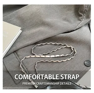 Détail de la chaîne en métal argenté entrelacée de cuir noir sur un sac bandoulière chic