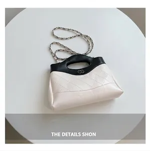 Détail macro du sac en cuir crème matelassé avec poignée noire et fermoir métal