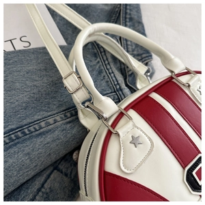 Detalle del bolso bandolera redondo de cuero rojo y blanco con adorno de estrella de metal