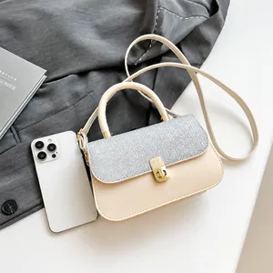 Detail of cream-colored small crossbody bag with silver textured flap and gold lock
