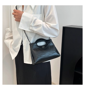 Détail du sac matelassé noir avec bandoulière chaîne et logo métallique sur mannequin