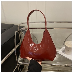 Detailed macro shot of the glossy burgundy hobo bag texture and sleek metallic shine