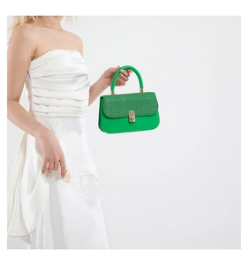 Detail of lime green mini handbag featuring sequined flap and golden twist lock closure