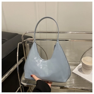 Macro shot of light blue glossy patent leather shoulder bag with FASHION embossed logo