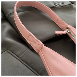 Close-up of pink shoulder bag showing reinforced X-stitch and silver metal zipper