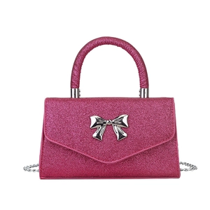 Sparkly pink crossbody bag with silver bow buckle and chain strap on white background