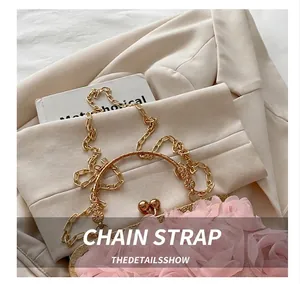 Detailed close-up of pink floral clutch featuring a gold ring handle and metal chain strap