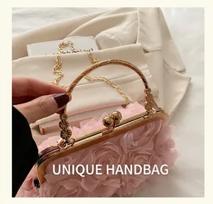 Detail of pink fabric evening bag with organza flowers and golden engraved handle