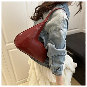 Close-up of deep red glossy leather shoulder bag with natural wrinkled texture details