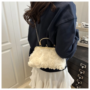 Detail of a white 3D fabric rose evening bag with a gold metal handle and chain