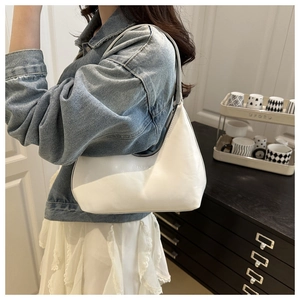 Detail of white glossy crescent bag featuring embossed FASHION text and metal zipper