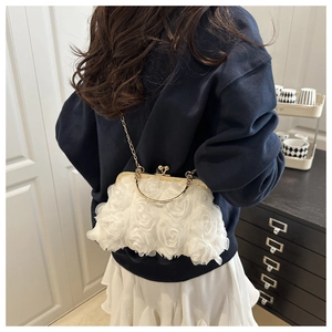 Macro shot of 3D white fabric rose flowers and vintage metal clasp on evening bag