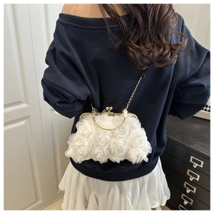 Detail of white 3D fabric roses on evening bag with gold metal frame and chain