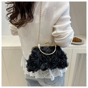 Detail of elegant black rose evening bag with gold chain and circular handle on model