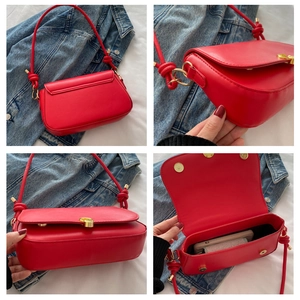 Detail view of red underarm bag featuring glossy finish, gold clasp, and knots decoration