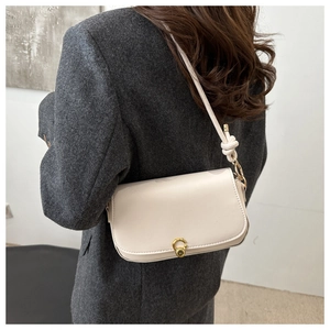 Detail of minimalist beige leather shoulder bag with gold twist lock and knot strap