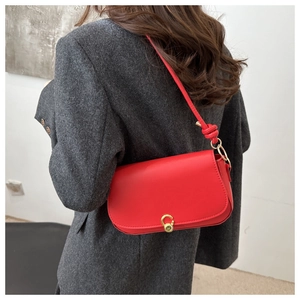 Close-up of red leather shoulder bag with golden round metal lock and knot strap detail