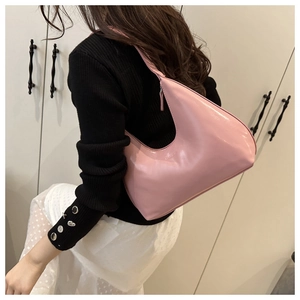 Side view of a trendy pink half-moon hobo bag worn by a model in a black outfit