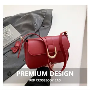 Nahaufnahme der roten Ledertasche mit goldener Hufeisenschnalle auf grauem Blazer