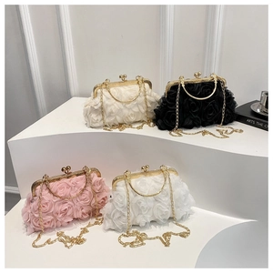 Detail of rose floral clutch bags in pink, black, and white with gold ring handles