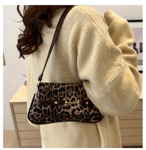 Détail du sac à bandoulière léopard avec boucle dorée porté sur un pull en maille