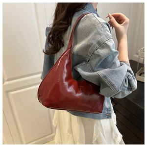 Detail of red patent leather hobo bag with glossy finish and embossed fashion logo