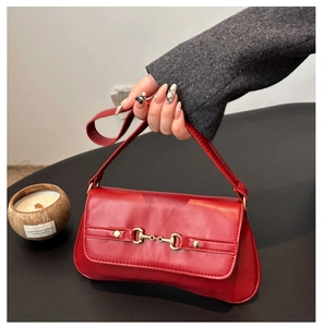 Détail d'un sac à bandoulière en similicuir rouge avec boucle mors dorée iconique