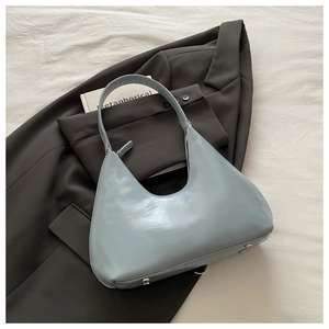 Detail of light blue minimalist leather shoulder bag on a stylish dark blazer