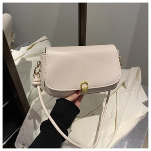 Detail view of cream leather underarm bag with gold circular lock and neat stitching