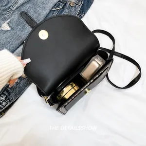 Interior view of black saddle bag with gold magnetic buckle and cosmetic storage space