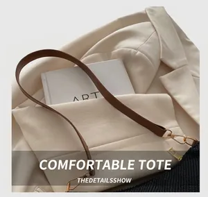Detail showing high-quality black woven texture with brown leather strap and gold hooks