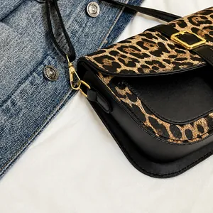 Close-up of leopard print saddle bag featuring gold hardware and black leather texture