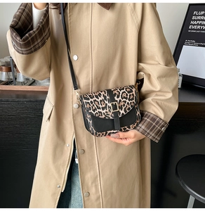 Detail of trendy leopard print saddle bag with metal buckle and black leather strap