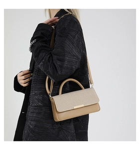Détail d'un sac à rabat beige avec fermoir doré, porté à l'épaule pour femme