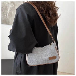 Detailed side view of a gray woven hobo bag with brown leather trim and metal hooks