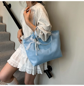 Detail van lichtblauwe grote shopper tas met kanten strik en parelhanger