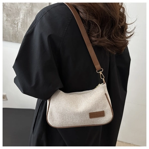 Detail of woven cream shoulder bag with brown leather trim and fashion label