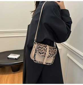 Detail of a leopard print saddle bag styled with a minimalist black coat for a chic look