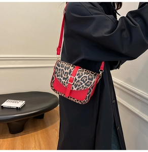 Detail of red leather saddle bag with leopard print panel and metal buckle closure