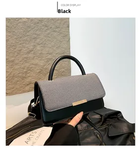 Détail du sac bandoulière noir avec rabat pied-de-poule et boucle dorée