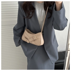 Gros plan sur le sac beige avec boucles de ceinture porté avec un blazer gris élégant