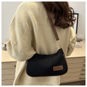 Detail of vintage canvas shoulder bag with brown leather trim and side brand patch