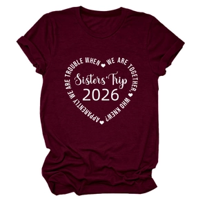 Détail du motif Sisters' Trip 2026 blanc sur un t-shirt en coton bordeaux à col rond
