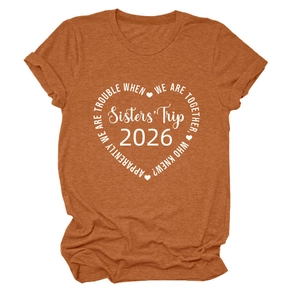 Détail du t-shirt orange avec imprimé cœur Sisters' Trip 2026 blanc et manches à revers fixés