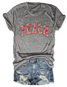 Flat lay of gray cotton T-shirt with strawberry TEACH print and ripped denim shorts