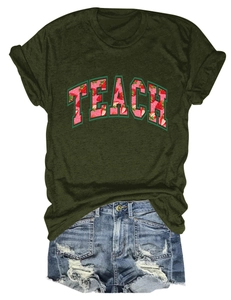 Olive green TEACH strawberry t-shirt paired with distressed denim shorts on white background