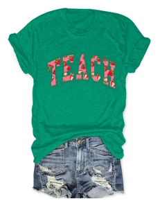 Detail of green cotton T-shirt featuring strawberry print TEACH text and denim shorts