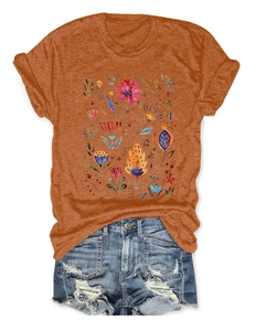 Flat lay of an orange crewneck T-shirt with floral prints and ripped denim shorts