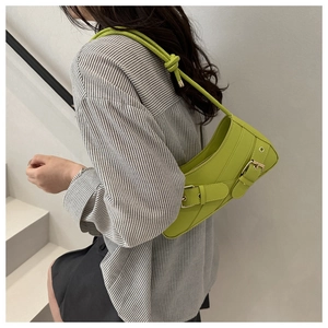 Détail du sac sous le bras vert néon avec boucles décoratives et bandoulière tressée