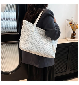 Détail du sac cabas blanc avec imprimé monogramme M gris et breloque métallique